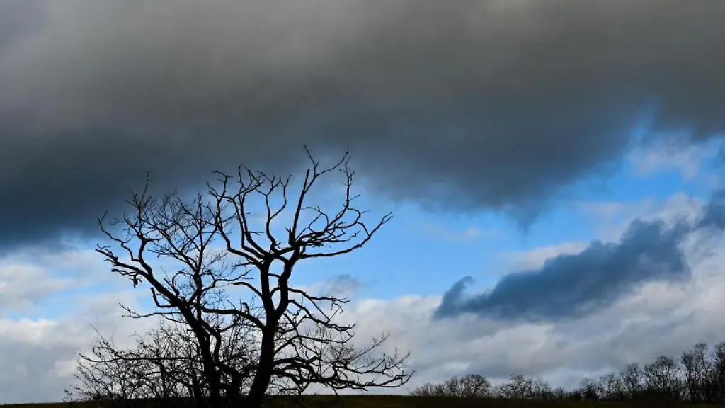 Dunkle-Wolken-ziehen-ueber-eine-Landschaft
