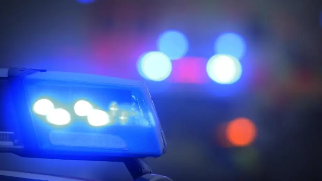 Ein-Polizeiauto-mit-eingeschaltetem-Blaulicht-steht-auf-einer-Strasse