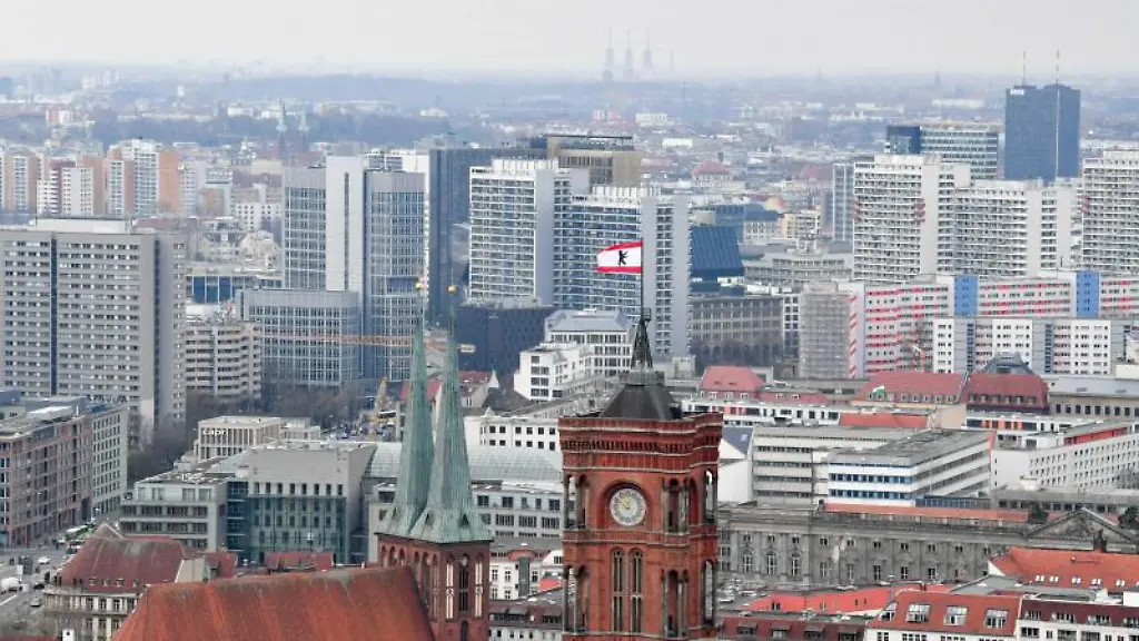 Hinter-den-Tuermen-der-Nikolaikirche-l-und-des-Roten-Rathauses-sind-zahlreiche-Wohnblocks-zu-sehen