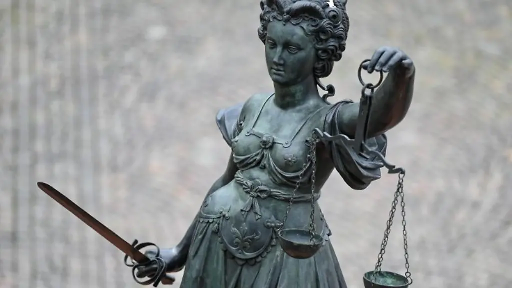 Die-Statue-der-Justitia-steht-mit-einer-Waage-und-einem-Schwert-in-der-Hand