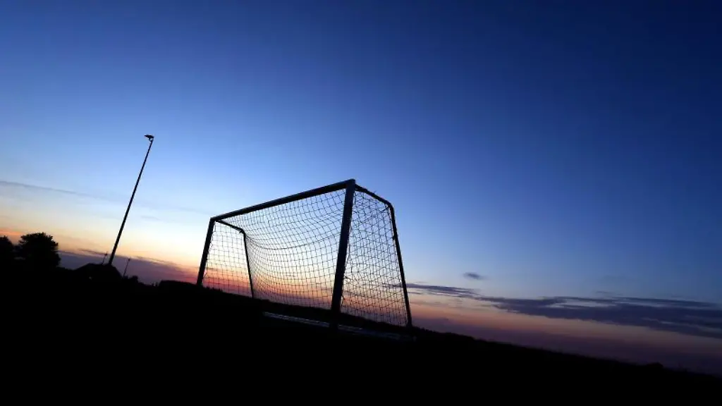 Ein-Fussballtor-hebt-sich-auf-dem-Sportplatz-zur-blauen-Stunde-vor-dem-wolkenlosem-Himmel-ab