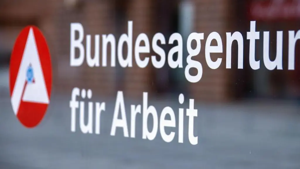 Das-Hinweisschild-fuer-die-Bundesagentur-fuer-Arbeit-ist-an-einer-Glasflaeche-vor-einem-Buerogebaeude-zu-sehen
