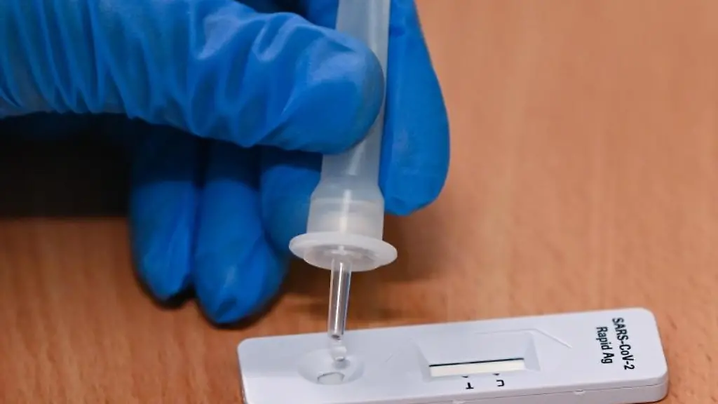 Eine-Mitarbeiterin-vom-Gesundheitsamt-tropft-eine-Fluessigkeit-auf-einen-Corona-Schnelltest