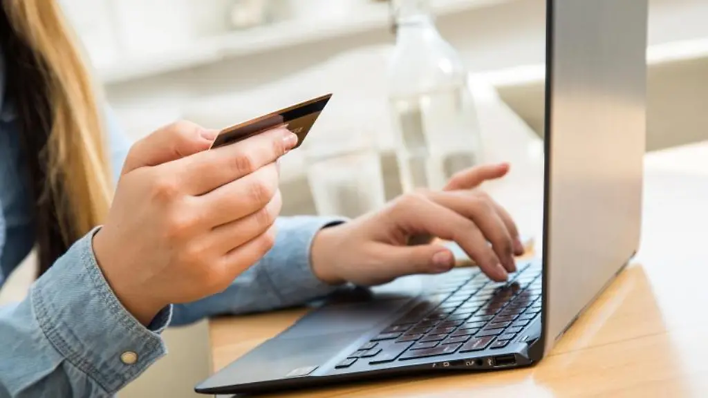 Eine-Frau-tippt-die-Nummer-ihrer-Kreditkarte-auf-einem-Laptop