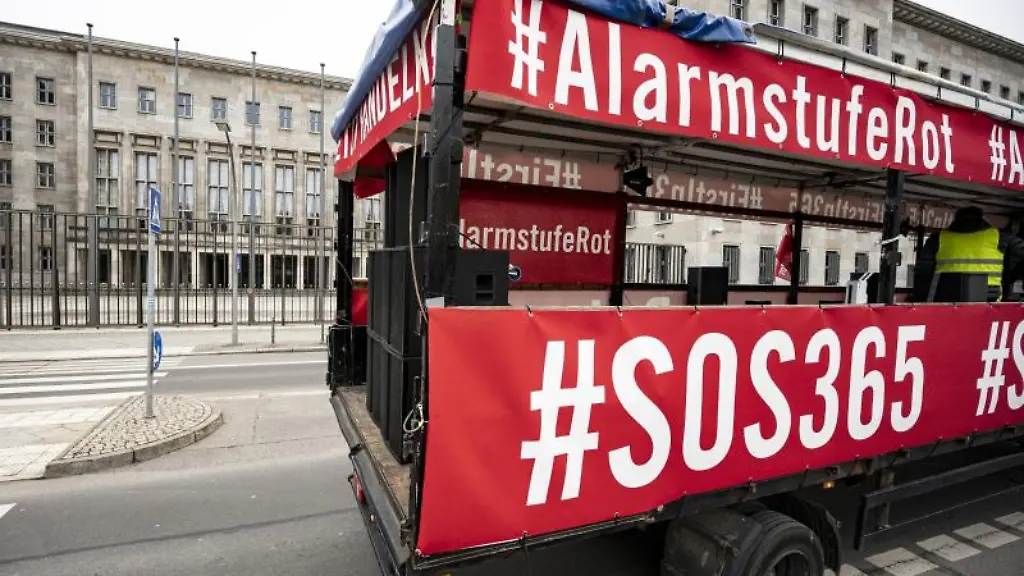 Eine-Lastwagen-mit-Bannern-mit-der-Aufschrift-AlarmstufeRot-und-SOS365-faehrt-bei-der-Demonstration-mit-einem-Autokorso-der-Veranstaltungsbranche-am-Bundesfinanzministerium-vorbei