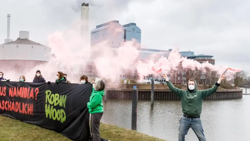 Aktivisten-der-Umweltschutzorganisation-Robin-Wood-demonstrieren-vor-dem-Kraftwerk-Tiefstack-hinter-einem-Transparent-mit-der-Aufschrift-Heizen-mit-Holz-aus-Namibia-Unfair-und-klimaschaedlich