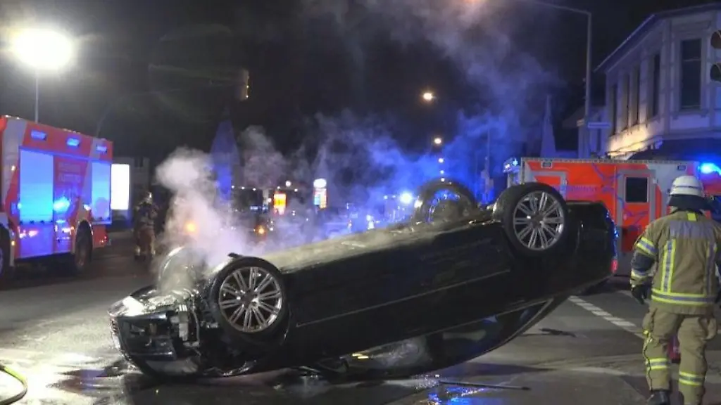 Einsatzkraefte-der-Feuerwehr-stehen-nach-einem-Unfall-mit-zwei-Fahrzeugen-vor-einem-der-Unfallwagen