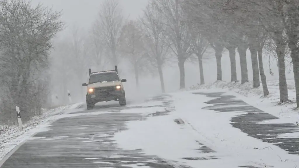 Ein-Auto-ist-im-Schneetreiben-auf-einer-Landstrasse-unterwegs