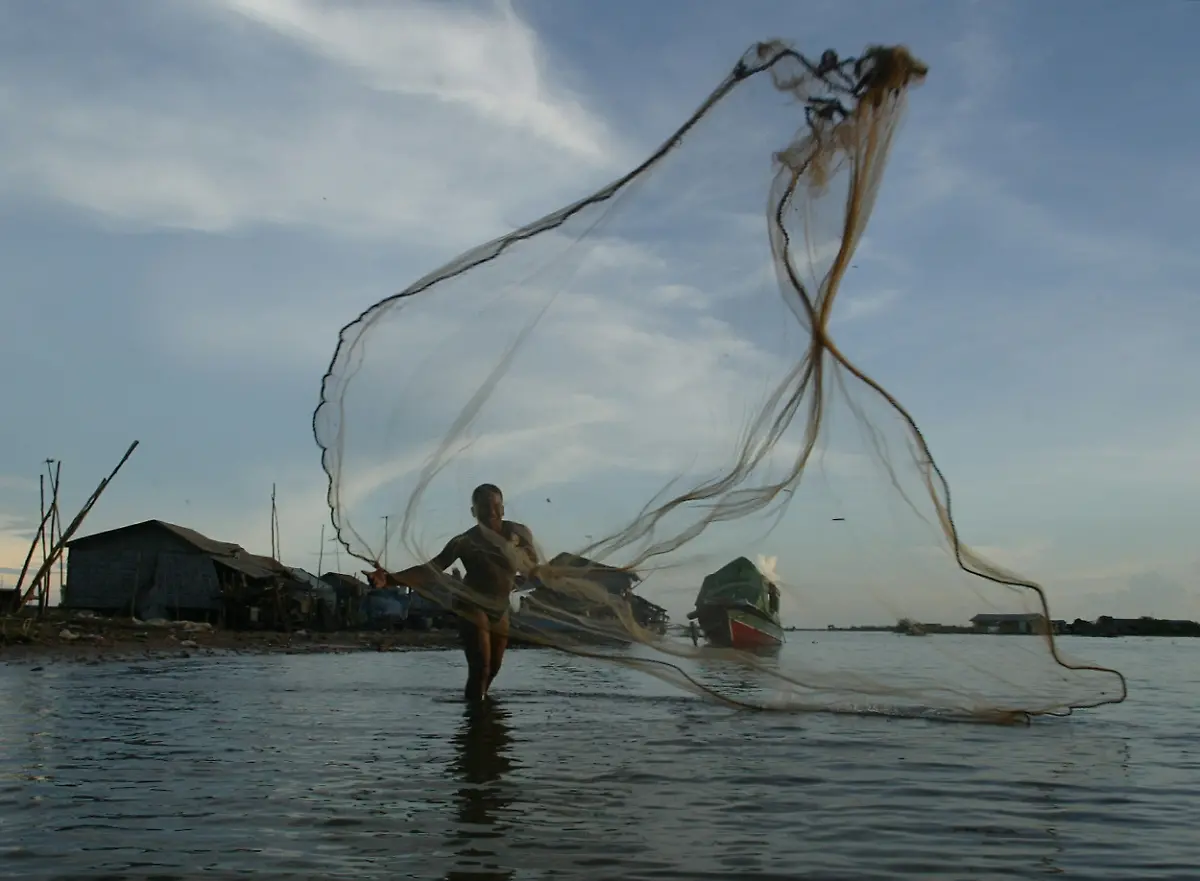 A-Khmer-fisherman-throws-his-handmade-net-at-the-Tonle-Sap-lake-in-Siem-Reap-Cambodia-October-28-2005-Tonle-Sap-southeast-Asia-s-biggest-lake-provides-about-50-of-Cambodia-s-total-freshwater-fish-production-and-a-direct-source-of-livelihood-for-more-than-1-million-people-living-on-and-around-the-lake-Fish-a-staple-part-of-the-Cambodians-diet-is-sold-for-1-to-5-per-kilo
