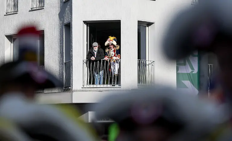 Ein-verkleideter-und-ein-nicht-verkleideter-Mann-stehen-auf-einem-Balkon-und-beobachten-Gardisten-Zum-Beginn-der-fuenften-Jahreszeit-werden-am-11-11-Tausende-Naerrinnen-und-Narren-in-Mainz-erwartet