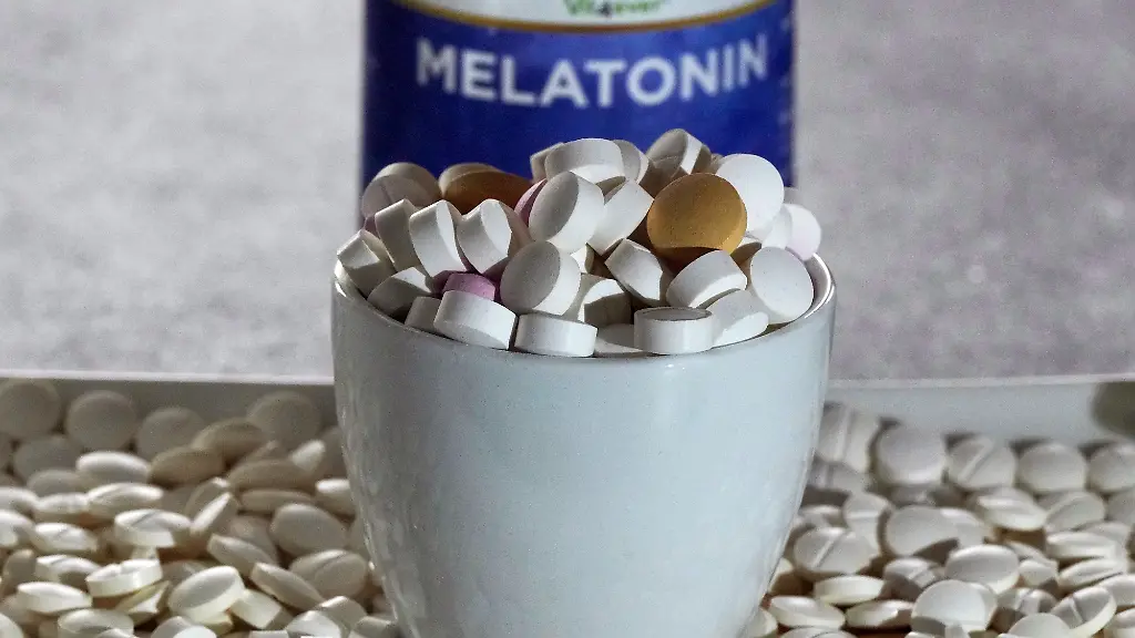 Tabletten-verschiedener-Hersteller-liegen-in-einer-Schale-vor-einer-Plastikdose-mit-der-Aufschrift-Melatonin