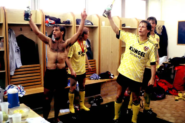 Ulf-Kirsten-mit-freiem-Oberkoerper-beim-Feiern-in-der-Kabine-rechts-Torsten-Guetschow