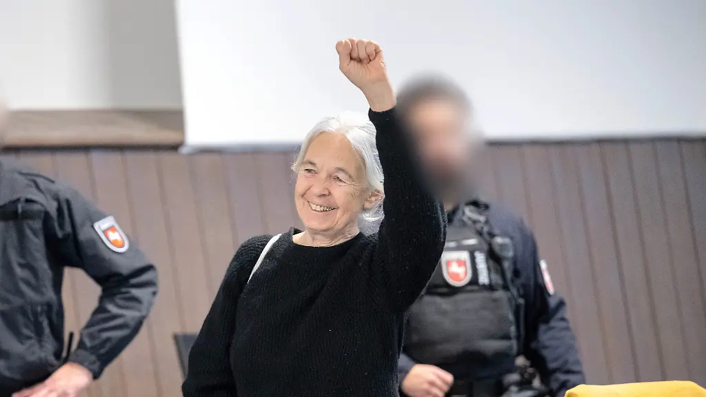 Die-Angeklagte-Daniela-Klette-reagiert-zu-Beginn-des-Verhandlungstages-auf-Unterstuetzer-im-Zuschauerbereich-des-provisorischen-Gerichtssaals-des-Landgerichts-Verden-in-Verden-Eitze-Die-fruehere-RAF-Terroristin-steht-seit-Ende-Maerz-wegen-einer-Serie-von-Ueberfaellen-auf-Supermaerkte-und-Geldtransporter-zwischen-1999-und-2016-vor-Gericht