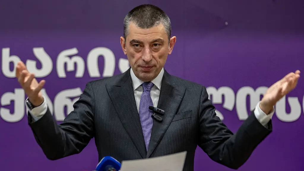 News-Bilder-des-Tages-At-the-conclusion-of-his-press-conference-Giorgi-Gakharia-opens-his-hands-in-a-broad-gesture-addressing-the-gathered-journalists-and-supporters-Standing-against-the-purple-backdrop-with-his-partys-emblem-he-makes-a-strong-closing-statement
