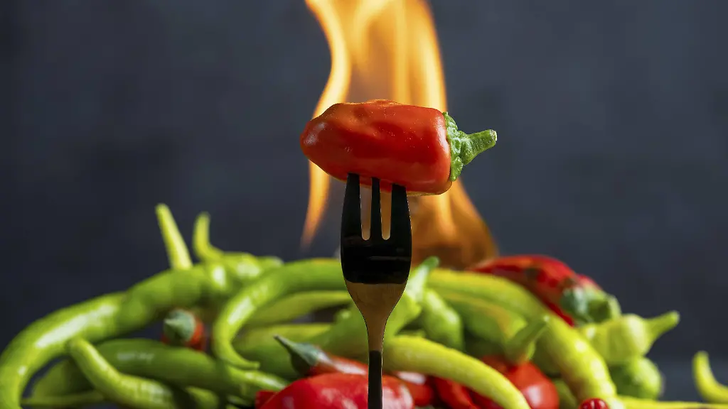 Ein-roter-Pfefferoni-auf-einer-Gabel-Pfefferoni-und-Feuer-im-Hintergrund-Foodfotografie-OrigBildgroesse-8192x5464-px