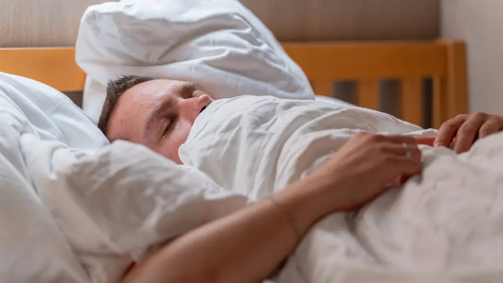 Germany-20-September-2025-A-man-lies-cuddled-up-in-bed-under-a-blanket-and-sleeps-peacefully-symbolizing-rest-relaxation-and-restful-sleep-in-everyday-life-Ein-Mann-liegt-im-Bett-eingekuschelt-unter-einer-Decke-und-schlaeft-friedlich-was-Ruhe-Entspannung-und-erholsamen-Schlaf-im-Alltag-symbolisiert