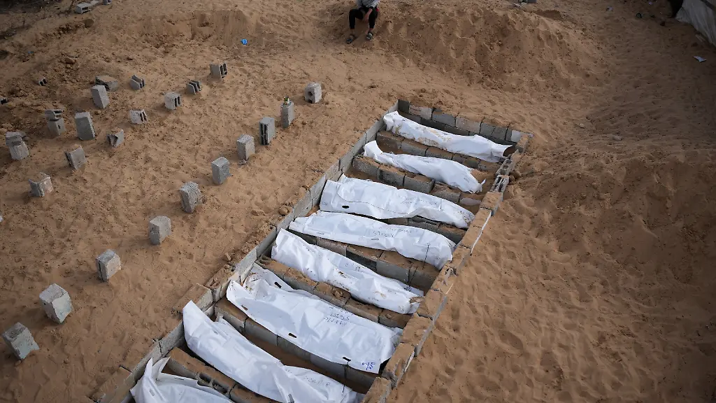 Children-watch-as-bodies-of-unidentified-Palestinians-returned-from-Israel-as-part-of-the-ceasefire-deal-are-buried-in-Deir-al-Balah-Gaza-Strip-Friday-Nov-14-2025