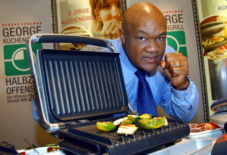 epa00560686-George-Foreman-former-world-champion-in-heavy-weight-boxing-presents-the-new-generation-of-his-kitchen-grill-Big-George-at-a-Karstadt-department-store-in-Dortmund-Germany-Tuesday-25-October-2005-In-1994-Foreman-became-the-oldest-boxing-world-champion-of-all-times-at-age-45-In-the-US-Foreman-became-more-famous-for-his-kitchen-grills-than-during-his-time-as-an-active-boxing-pro