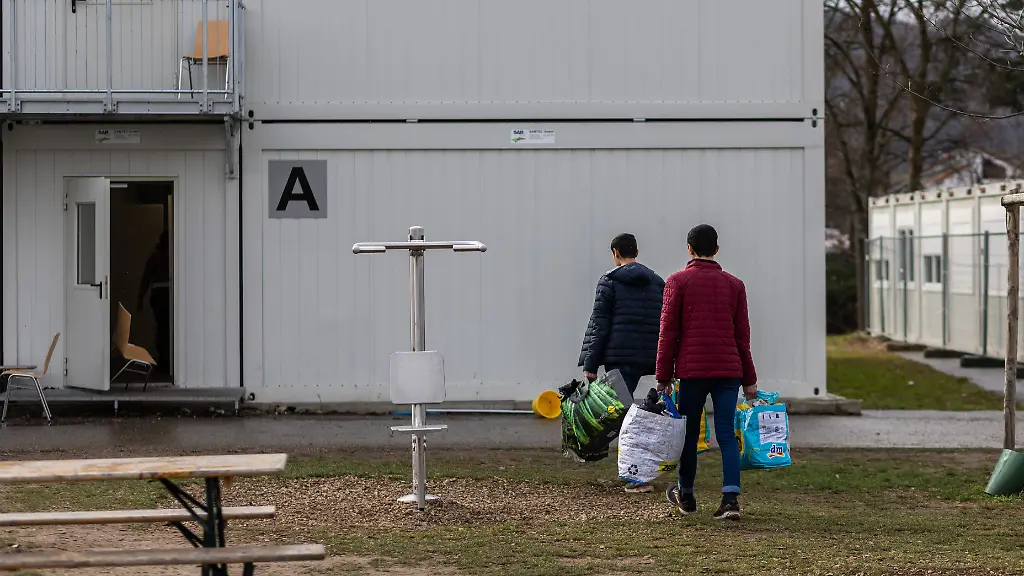 Zwei-Bewohner-der-Landeserstaufnahmeeinrichtung-LEA-gehen-mit-Plastiktueten-ueber-das-Gelaende-der-Einrichtung-In-der-Landeserstaufnahmeeinrichtung-LEA-war-es-mehrfach-zu-Krawallen-gekommen-ein-28-Jaehriger-wurde-bereits-zu-einer-Bewaehrungsstrafe-verurteilt