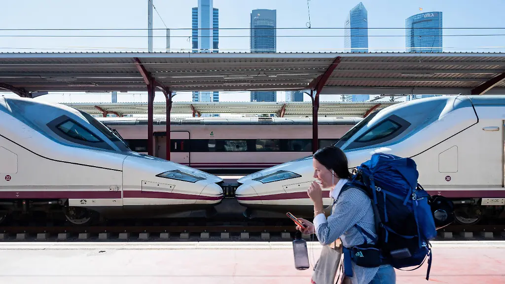 A-passenger-walks-past-a-high-speed-train-from-Spain-s-national-state-owned-railway-company-Renfe-specifically-the-Ave-is-on-the-platform-at-Chamartin-Clara-Campoamor-train-station-with-Madrid-s-skyline-seen-in-the-background