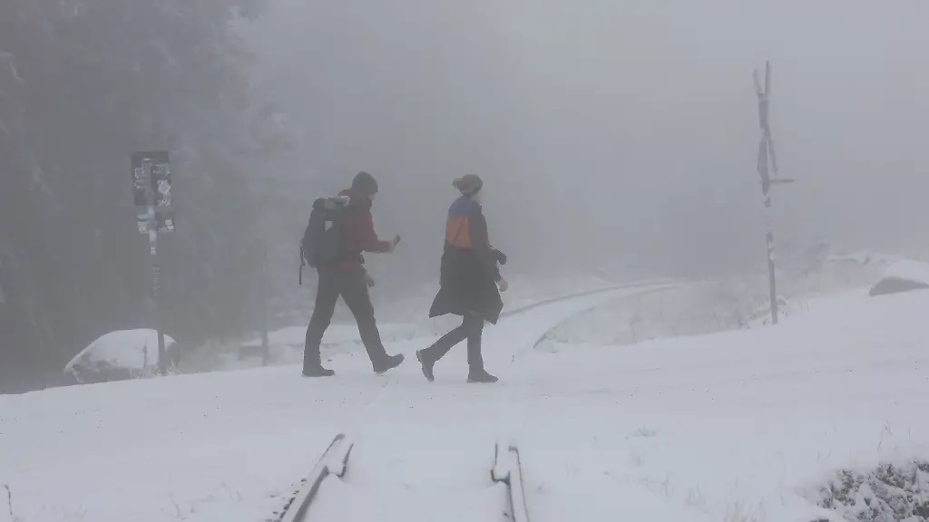 Wanderer-gehen-auf-der-Brockenstrasse-durch-eine-winterliche-Landschaft-In-den-hoeheren-Lagen-des-Harzes-ist-es-winterlich-geworden