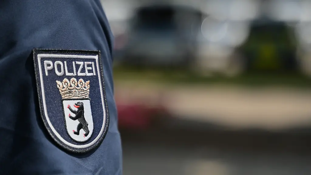 Ein-Polizist-traegt-eine-Uniform-mit-dem-Berliner-Polizeilogo-auf-dem-Hemdenaermel