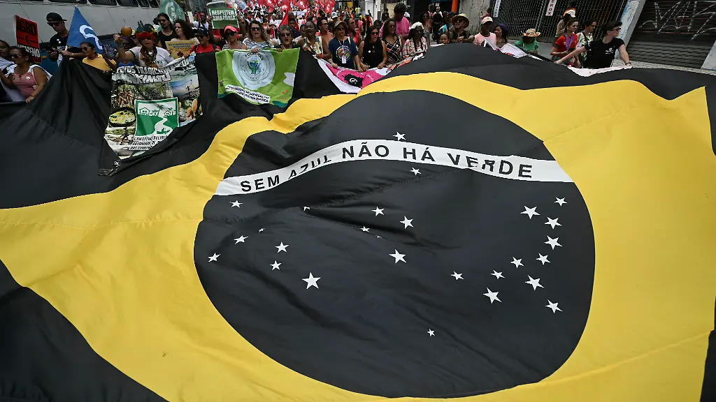 Activists-hold-a-huge-black-and-yellow-Brazilian-flag-reading-Without-blue-there-is-no-green-during-the-so-called-Great-People-s-March-in-the-sidelines-of-the-COP30-UN-Climate-Change-Conference-in-Belem-Para-State-Brazil-on-November-15-2025-Thousands-of-people-attended-the-march-to-demand-real-solutions-to-human-caused-global-warming-and-which-comes-at-the-halfway-point-of-contentious-COP30-negotiations-following-two-Indigenous-led-protests-that-disrupted-proceedings-earlier-in-the-week