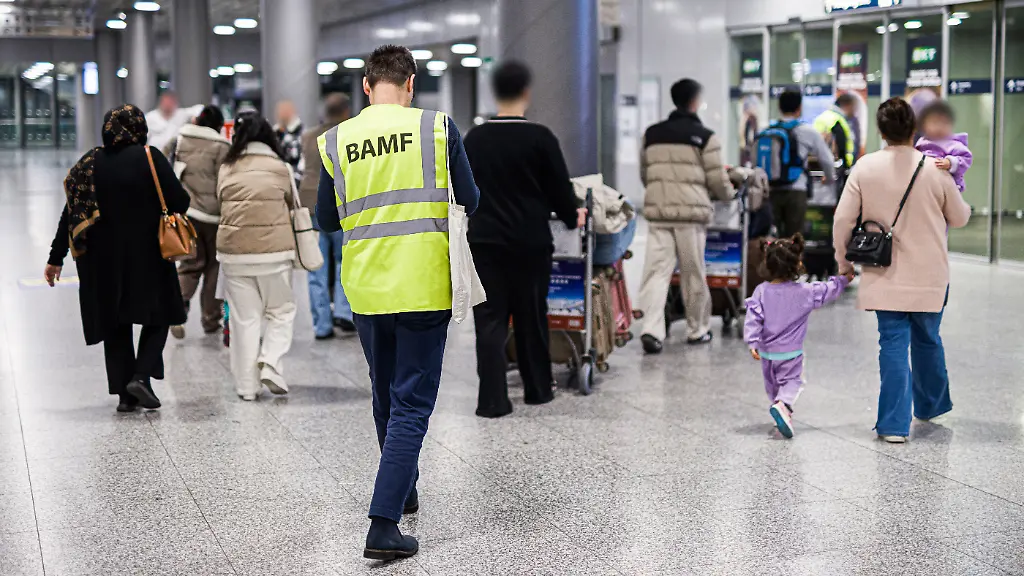 Menschen-aus-Afghanistan-die-zuvor-mit-einem-Flugzeug-auf-dem-Flughafen-Hannover-Langenhagen-gelandet-sind-werden-von-einem-Mitarbeiter-des-Bundesamtes-fuer-Migration-und-Fluechtlinge-BAMF-durch-den-Flughafen-begleitet-Die-afghanischen-Staatsangehoerige-haben-eine-Aufnahmezusage-fuer-Deutschland