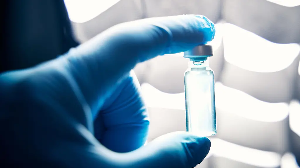 Arzt-haelt-mit-Schutzhandschuhen-in-einem-Labor-eine-Ampulle-mit-einem-Impfstoff
