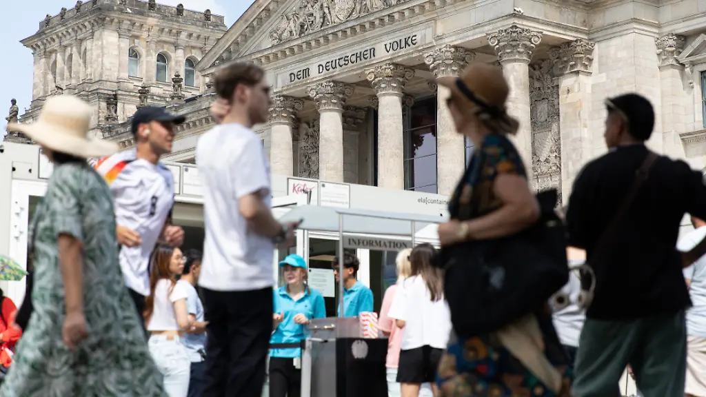 July-20-2025-Berlin-Berlin-Germany-Tourists-and-Berliners-gathered-outside-the-Reichstag-building-in-Berlin-on-Sunday-July-20-2025-as-Germany-s-iconic-seat-of-democracy-stood-in-sharp-contrast-to-the-economic-uncertainty-gripping-the-nation-Families-posed-for-selfies-and-visitors-lingered-by-the-Spree-River-unaware-perhaps-that-just-beyond-those-walls-one-of-the-most-profound-fiscal-reckonings-in-postwar-German-history-is-unfolding-Chancellor-Friedrich-Merz-facing-mounting-criticism-at-home-and-abroad-has-called-for-sweeping-austerity-measures-after-Germany-s-public-debt-soared-past-A-aA-2-7-trillion-with-projections-climbing-toward-A-aA-3-7-trillion-over-the-next-decade-Despite-record-tax-revenues-budgetary-shortfalls-persist-as-social-security-systems-particularly-pensions-and-healthcare-place-unprecedented-strain-on-the-federal-budget-Public-trust-is-wearing-thin-as-citizens-question-where-decades-of-record-taxation-have-gone-With-infrastructure-decaying-and-education-systems-strained-many-ask-how-can-one-of-Europe-s-strongest-economies-be-this-indebted-Sunday-s-calm-outside-the-Reichstag-belied-the-fiscal-storm-brewing-within