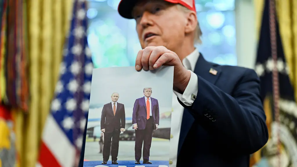 August-22-2025-Washington-District-Of-Columbia-USA-United-States-President-Donald-J-Trump-holds-a-photo-of-himself-with-President-Vladimir-Putin-of-the-Russian-Federation-in-Alaska-after-announcing-the-2026-World-Cup-draw-will-be-held-at-the-Kennedy-Center-in-December-in-the-Oval-Office-of-the-White-House-in-Washington-DC-on-Friday-August-22-2025-The-FIFA-World-Cup-coming-to-North-America-next-summer-will-be-the-first-World-Cup-with-three-host-countries-in-the-U-S