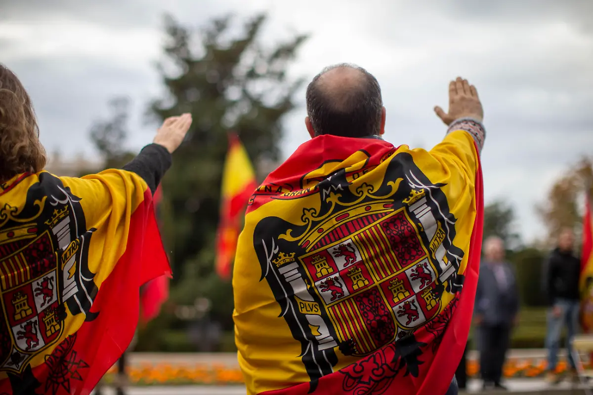 Supporters-with-Francoist-flags-around-their-necks-raise-their-right-hands-while-singing-Cara-al-Sol-during-a-rally-commemorating-the-anniversary-of-the-death-of-dictator-Francisco-Franco-on-November-20-1975-and-of-Jose-Antonio-Primo-de-Rivera-on-November-20-1936-founder-of-the-right-wing-group-Falange-Espanola-in-the-Plaza-de-Oriente-in-Madrid