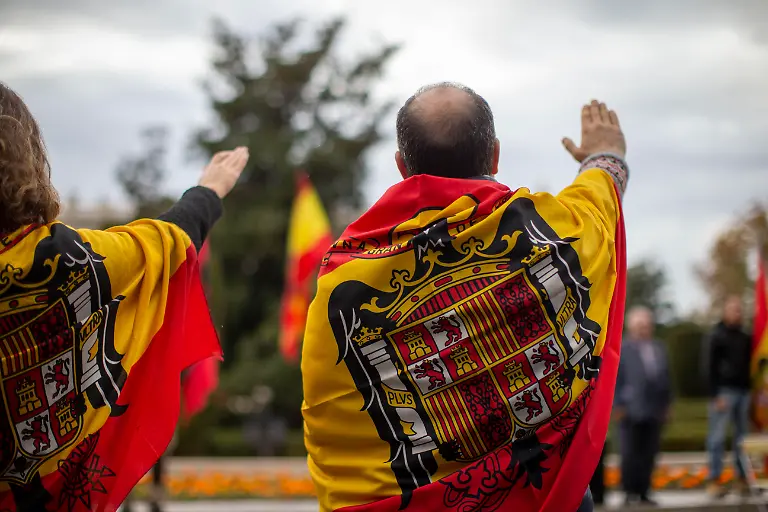 Supporters-with-Francoist-flags-around-their-necks-raise-their-right-hands-while-singing-Cara-al-Sol-during-a-rally-commemorating-the-anniversary-of-the-death-of-dictator-Francisco-Franco-on-November-20-1975-and-of-Jose-Antonio-Primo-de-Rivera-on-November-20-1936-founder-of-the-right-wing-group-Falange-Espanola-in-the-Plaza-de-Oriente-in-Madrid
