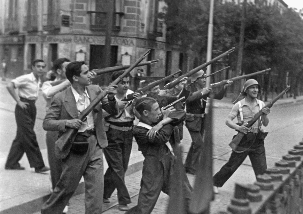 Kaempfer-in-Zivil-der-republiktreuen-Volksfront-begeben-sich-im-Sommer-1936-kurz-nach-Ausbruch-des-Spanischen-Buergerkriegs-angeleitet-durch-den-franzoesischen-Pressefotografen-in-arrangierte-Angriffspositur-Im-Hintergrund-eine-Filiale-der-Banco-Bizcaya-heutiges-Bankhaus-BBVA-Aufnahme-vermutlich-aus-Bilbao-Baskenland-Spanien-Nach-dem-Buergerkriegsausbruch-am-17-Juni-1936-kam-es-in-vielen-grossen-Staedten-Spaniens-zu-Strassenkaempfen-zwischen-Republikanern-Kommunisten-und-Nationalisten-Aufnahmedatum-01-06-1936-31-12