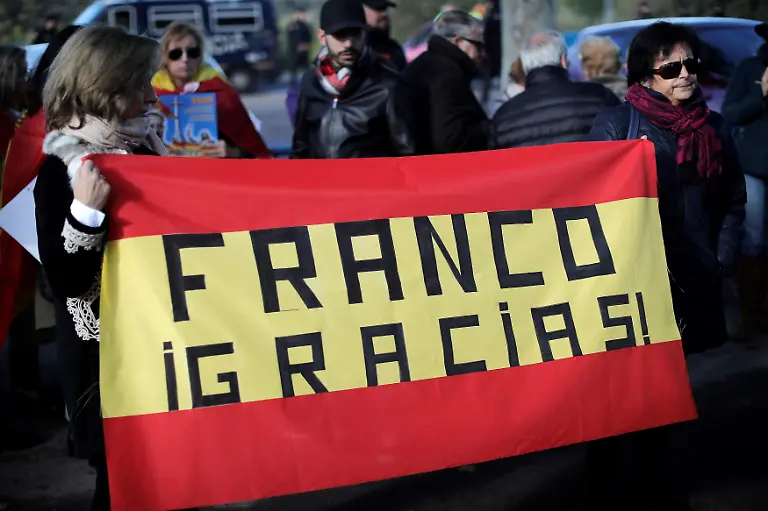 MADRID-SPAIN-OCTOBER-24-Supporters-of-Francisco-Franco-hold-Spanish-flags-as-people-gather-near-Mingorrubio-cemetery-before-Franco-s-exhumation-in-El-Pardo-district-outside-Madrid-Spain-on-October-24-2019-Body-of-Spain-s-former-dictator-Fransisco-Franco-to-be-moved-from-Valley-of-Fallen-monument-to-Mingorrubio-cemetery-outside-Madrid-at-El-Pardo-district