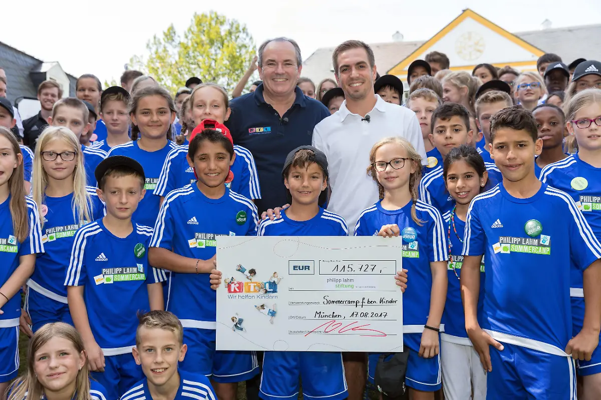 Was-fuer-eine-Ueberraschung-fuer-die-80-Kinder-im-Philipp-Lahm-r-Sommercamp-bei-Muenchen-Philipp-Lahm-hoechstpersoenlich-ist-da-Und-der-Fussballstar-ist-nicht-alleine-gekommen-RTL-Wir-helfen-Kindern-Vorstand-Wolfram-Kons-ist-mit-dabei-um-der-Philipp-Lahm-Stiftung-fuer-die-Fortfuehrung-der-Sommercamps-einen-Spendenscheck-in-Hoehe-von-115-727-Euro-zu-ueberreichen-Die-Verwendung-des-sendungsbezogenen-Materials-ist-nur-mit-dem-Hinweis-und-Verlinkung-auf-RTL-gestattet