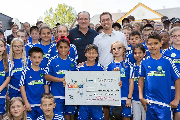 Was-fuer-eine-Ueberraschung-fuer-die-80-Kinder-im-Philipp-Lahm-r-Sommercamp-bei-Muenchen-Philipp-Lahm-hoechstpersoenlich-ist-da-Und-der-Fussballstar-ist-nicht-alleine-gekommen-RTL-Wir-helfen-Kindern-Vorstand-Wolfram-Kons-ist-mit-dabei-um-der-Philipp-Lahm-Stiftung-fuer-die-Fortfuehrung-der-Sommercamps-einen-Spendenscheck-in-Hoehe-von-115-727-Euro-zu-ueberreichen-Die-Verwendung-des-sendungsbezogenen-Materials-ist-nur-mit-dem-Hinweis-und-Verlinkung-auf-RTL-gestattet
