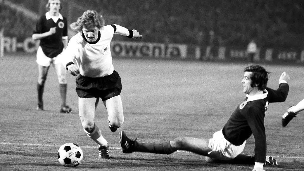 Der-deutsche-Stuermer-Dieter-Herzog-l-ueberlaeuft-den-schottischen-Abwehrspieler-Al-Jardine-Die-deutsche-Fussballnationalmannschaft-besiegt-am-27-03-1974-vor-60-000-Zuschauern-im-Frankfurter-Waldstadion-Schottland-im-Laenderspiel-mit-2-1