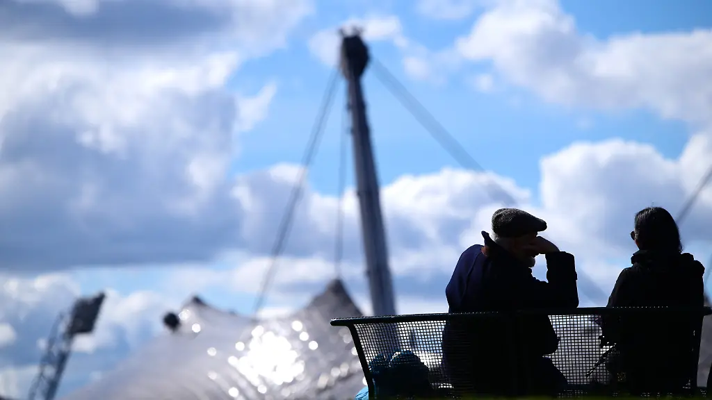 Muenchen-11-3-2024-Schmuckfoto-Symbolfoto-Ein-Mann-und-eine-Frau-sitzen-auf-einer-Bank-im-Muenchner-Olympiapark-Im-Hintergrund-das-Olympiastadion