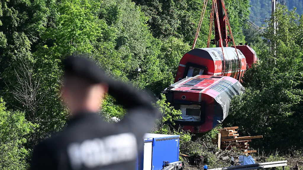 Ein-Polizist-betrachtet-aus-der-Ferne-den-Unfallort-wo-zwei-Waggons-noch-geborgen-werden-muessen-Bei-der-Entgleisung-einer-Regionalbahn-in-Garmisch-Partenkirchen-waren-Anfang-Juni-fuenf-Menschen-gestorben-Mehr-als-fuenf-Monate-nach-dem-Unglueck-nimmt-die-Bahn-nun-am-Mittwoch-16-11-wieder-den-Verkehr-auf-der-reparierten-Strecke-auf