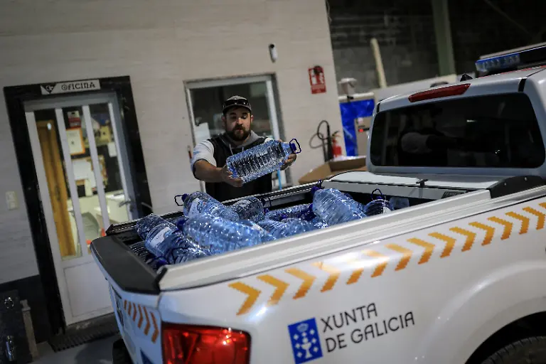 Volunteer-and-taxi-driver-Simon-Rodriguez-33-throws-5-liter-jugs-of-bottled-water-in-the-trunk-of-a-car-for-local-residents-after-seasonal-rains-washed-down-ash-and-sediment-from-a-wildfire-in-August-making-the-water-unsafe-for-cooking-and-drinking-in-San-Vicente-de-Leira-Galicia-Spain-November-7-2025-As-the-seasonal-October-rains-picked-up-the-entire-vegetative-layer-which-had-turned-to-ash-began-to-clog-the-sandtraps-known-locally-as-areneros-that-decant-rainwater-to-prevent-debris-from-reaching-the-water-line-feeding-the-reservoir-We-can-t-shower-because-the-water-is-completely-black-I-haven-t-showered-in-two-days-We-have-to-wait-for-the-rain-to-stop-before-we-can-shower-Rodriguez-said-while-delivering-drinking-water-to-residents-in-the-municipality-of-Villamartin-de-Valdeorras-who-have-been-advised-since-late-October-to-avoid-using-water-for-cooking-or-drinking-REUTERS-Nacho-Doce-SEARCH-IBERIA-WILDFIRES-AFTERMATH-FOR-THIS-STORY-SEARCH-WIDER-IMAGE-FOR-ALL-STORIES