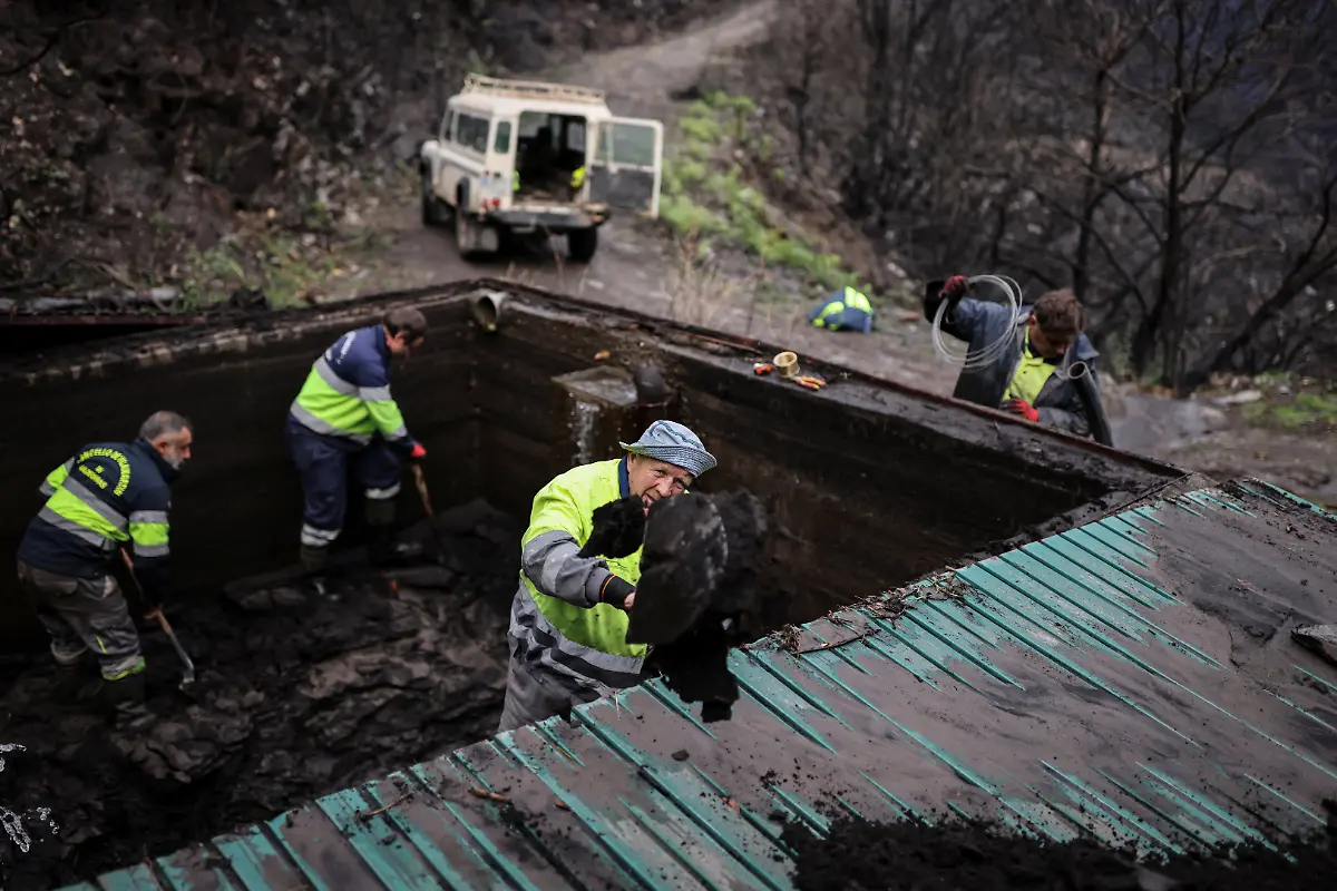 From-left-to-right-Raul-Lopez-53-Luis-Cuadrdao-45-Oleksandr-Bulavenko-59-and-Jose-Luis-53-use-shovels-to-clean-and-unclog-a-sandtrap-or-arenero-from-the-ash-and-mud-dragged-by-seasonal-rains-after-a-wildfire-in-August-in-the-municipality-of-Villamartin-de-Valdeorras-Galicia-Spain-November-7-2025-As-the-seasonal-October-rains-picked-up-the-entire-vegetative-layer-which-had-turned-to-ash-began-to-clog-the-sandtraps-known-locally-as-areneros-that-decant-rainwater-to-prevent-debris-from-reaching-the-water-line-feeding-the-reservoir-We-have-been-here-for-almost-a-month-working-to-remove-the-ash-mixed-with-mud-said-Raul-Lopez-a-worker-for-the-municipality-We-have-never-seen-a-disaster-like-this-before-in-our-lives-Neither-my-grandfather-nor-my-father-nor-anyone-else-can-remember-a-disaster-like-this-REUTERS-Nacho-Doce-SEARCH-IBERIA-WILDFIRES-AFTERMATH-FOR-THIS-STORY-SEARCH-WIDER-IMAGE-FOR-ALL-STORIES