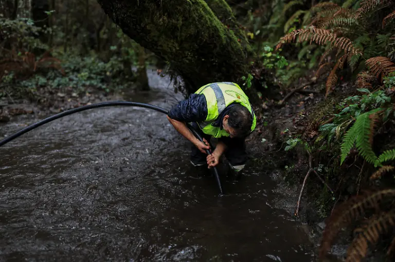 Domingo-Prieto-Martinez-56-uses-a-tube-to-unclog-sandtrap-or-arenero-pipes-from-ash-dragged-by-seasonal-rains-after-a-wildfire-in-August-in-the-municipality-of-Villamartin-de-Valdeorras-Galicia-Spain-November-7-2025-As-the-seasonal-October-rains-picked-up-the-entire-vegetative-layer-which-had-turned-to-ash-began-to-clog-the-sandtraps-known-locally-as-areneros-that-decant-rainwater-to-prevent-debris-from-reaching-the-water-line-feeding-the-reservoir-We-have-been-here-for-almost-a-month-working-to-remove-the-ash-mixed-with-mud-said-Raul-Lopez-a-worker-for-the-municipality-We-have-never-seen-a-disaster-like-this-before-in-our-lives-Neither-my-grandfather-nor-my-father-nor-anyone-else-can-remember-a-disaster-like-this-REUTERS-Nacho-Doce-SEARCH-IBERIA-WILDFIRES-AFTERMATH-FOR-THIS-STORY-SEARCH-WIDER-IMAGE-FOR-ALL-STORIES