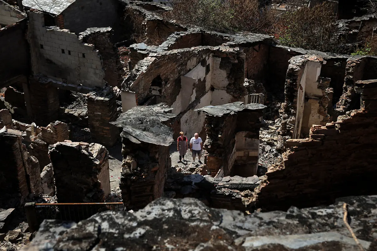 Ana-Sanchez-left-68-and-her-husband-Leopoldo-Nogueira-78-stand-in-front-of-the-ruins-of-their-home-surrounded-by-the-rubble-of-neighboring-houses-destroyed-by-a-wildfire-that-swept-through-the-village-of-San-Vicente-de-Leira-Galicia-Spain-September-17-2025-Although-the-record-breaking-wildfires-that-ripped-across-Spain-and-Portugal-in-August-have-subsided-residents-in-rural-communities-in-Spain-s-northwestern-Galicia-region-are-still-battling-the-aftermath-The-flames-were-much-higher-than-the-pine-trees-they-were-approaching-at-an-incredible-speed-and-in-less-than-five-minutes-the-fire-was-close-by-At-that-moment-I-decided-to-leave-said-Nogueira-The-day-after-they-almost-passed-out-from-the-pain-of-seeing-this-REUTERS-Violeta-Santos-Moura-SEARCH-IBERIA-WILDFIRES-AFTERMATH-FOR-THIS-STORY-SEARCH-WIDER-IMAGE-FOR-ALL-STORIES
