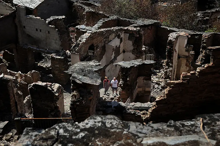 Ana-Sanchez-left-68-and-her-husband-Leopoldo-Nogueira-78-stand-in-front-of-the-ruins-of-their-home-surrounded-by-the-rubble-of-neighboring-houses-destroyed-by-a-wildfire-that-swept-through-the-village-of-San-Vicente-de-Leira-Galicia-Spain-September-17-2025-Although-the-record-breaking-wildfires-that-ripped-across-Spain-and-Portugal-in-August-have-subsided-residents-in-rural-communities-in-Spain-s-northwestern-Galicia-region-are-still-battling-the-aftermath-The-flames-were-much-higher-than-the-pine-trees-they-were-approaching-at-an-incredible-speed-and-in-less-than-five-minutes-the-fire-was-close-by-At-that-moment-I-decided-to-leave-said-Nogueira-The-day-after-they-almost-passed-out-from-the-pain-of-seeing-this-REUTERS-Violeta-Santos-Moura-SEARCH-IBERIA-WILDFIRES-AFTERMATH-FOR-THIS-STORY-SEARCH-WIDER-IMAGE-FOR-ALL-STORIES