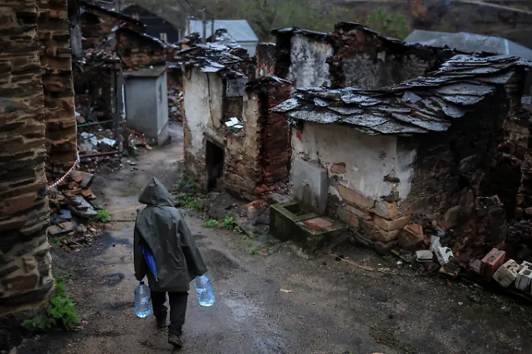 Neighbour-Jose-Nogueira-74-carries-two-5-liter-jugs-for-drinking-and-cooking-after-seasonal-rains-washed-down-ash-and-sediment-from-a-wildfire-in-August-making-the-water-unsafe-for-cooking-and-drinking-in-San-Vicente-de-Leira-Galicia-Spain-November-7-2025-As-the-seasonal-October-rains-picked-up-the-entire-vegetative-layer-which-had-turned-to-ash-began-to-clog-the-sandtraps-known-locally-as-areneros-that-decant-rainwater-to-prevent-debris-from-reaching-the-water-line-feeding-the-reservoir-We-can-t-shower-because-the-water-is-completely-black-I-haven-t-showered-in-two-days-We-have-to-wait-for-the-rain-to-stop-before-we-can-shower-Simon-Rodriguez-33-said-while-delivering-drinking-water-to-residents-in-the-municipality-of-Villamartin-de-Valdeorras-who-have-been-advised-since-late-October-to-avoid-using-water-for-cooking-or-drinking-REUTERS-Nacho-Doce-SEARCH-IBERIA-WILDFIRES-AFTERMATH-FOR-THIS-STORY-SEARCH-WIDER-IMAGE-FOR-ALL-STORIES