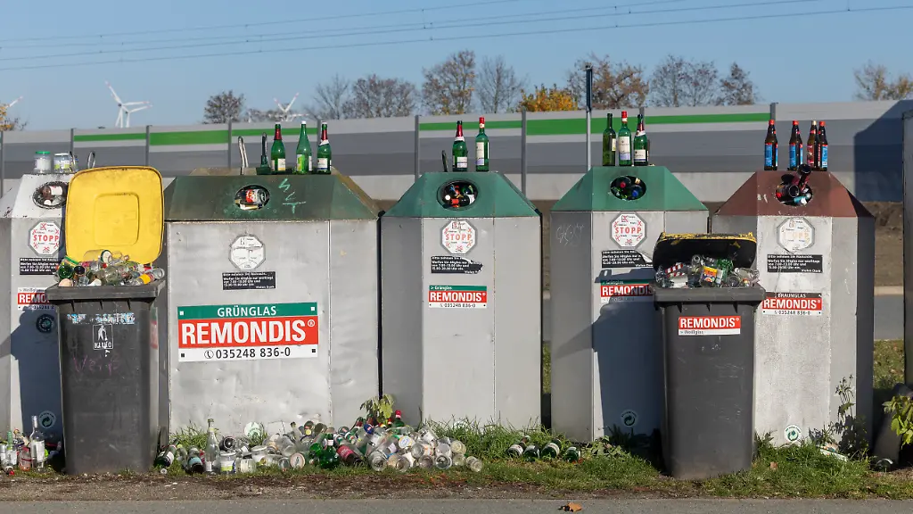 Mehrere-Altglascontainer-und-zusaetzliche-Muelltonnen-sind-uebervoll-so-dass-die-Anwohner-ihre-Flaschen-davor-darauf-und-daneben-stellen
