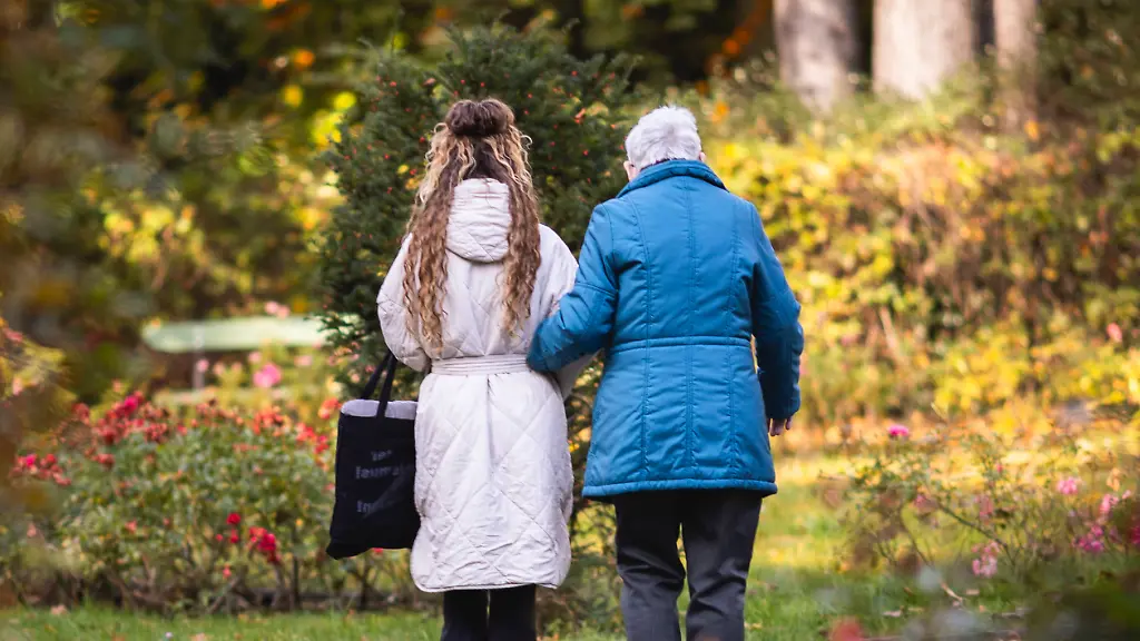 Eine-junge-Frau-und-eine-Seniorin-machen-einen-morgendlichen-Spaziergang-durch-einen-Park-aufgenommen-in-Berlin-20-10-2025