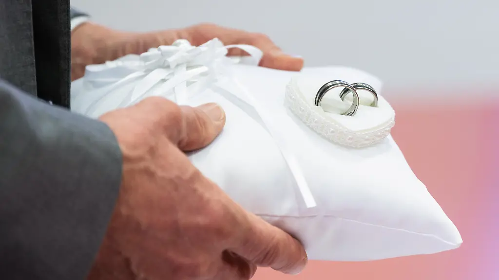 Zwei-Eheringe-sind-waehrend-einer-standesamtlichen-Trauung-auf-dem-Ringkissen-befestigt-Das-Durchschnittsalter-bei-der-ersten-Heirat-ist-in-Deutschland-auf-einen-Hoechststand-gestiegen