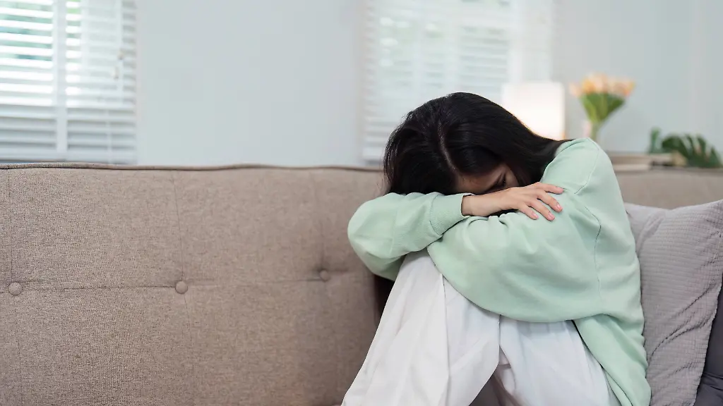 Woman-Feeling-Unwell-Sitting-on-Couch-in-Comfortable-Home-Setting-Expressing-Sickness-and-Discomfort-in-a-Cozy-Living-Room-Environment-A-woman-in-casual-clothing-sits-on-a-couch-appearing-unwell-and-sick-in-a-cozy-home-setting-conveying-themes-of-healthcare-and-illness-model-released-64022026